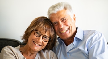 Smiling older couple posing together in professional portrait setting for dental practice.